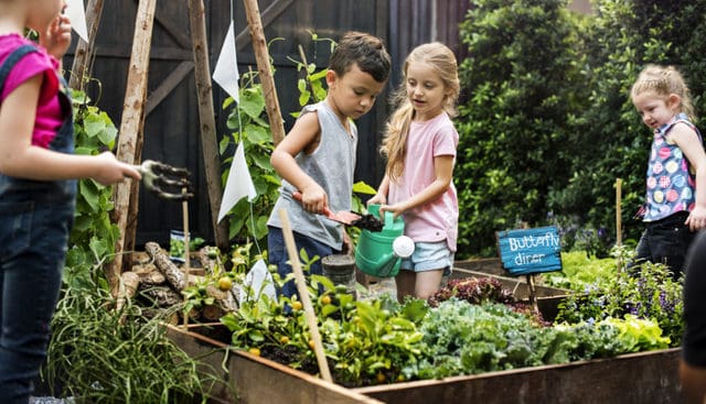 bambini che giocano in giardino e in orto annaffiando le piante